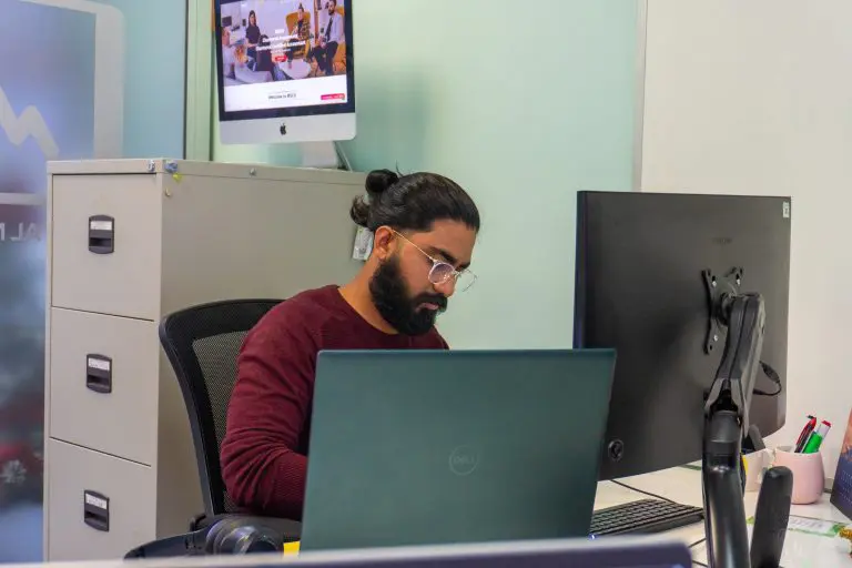 Person working on a laptop in a modern office, reviewing brand design and marketing materials