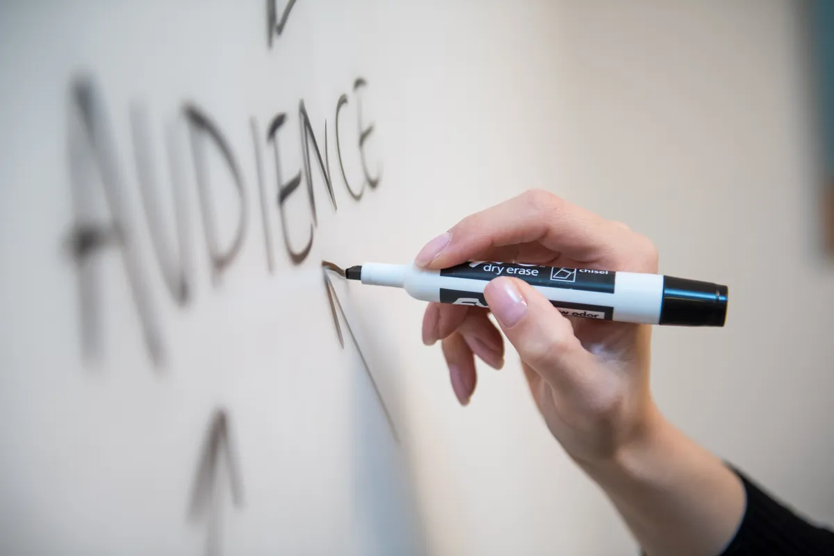 person writing audience on a whiteboard