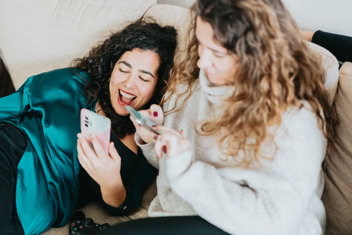 two girls sitting on the sofa with their phones